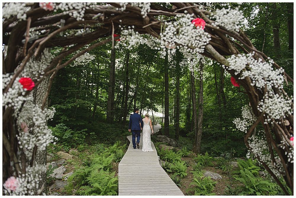 Groom kissing bride's cheek; she holds flowers. They are outdoors, near a tree. She wears a veil and dress, he wears a suit.