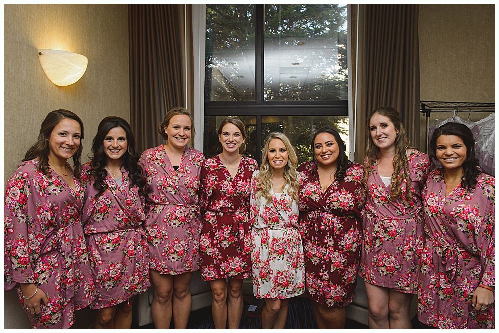 Woman putting on earrings, smiling. Dark background, wearing wedding dress.