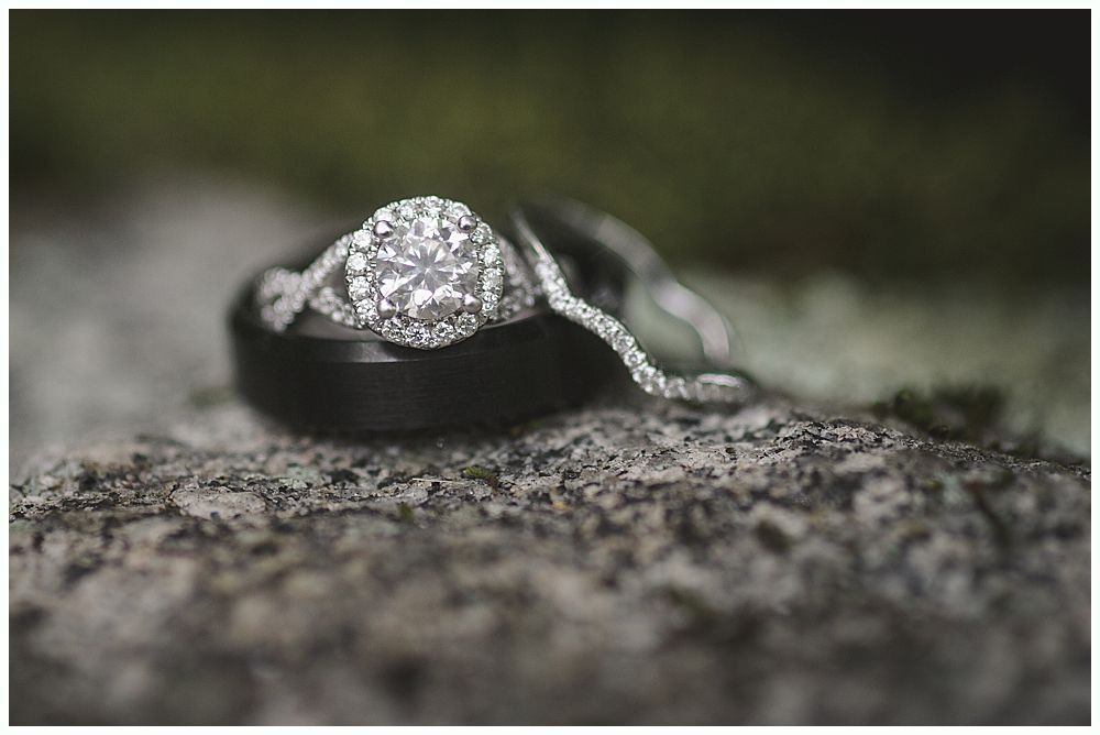 Bride and groom kiss under a weeping willow tree, backlit by sunlight.