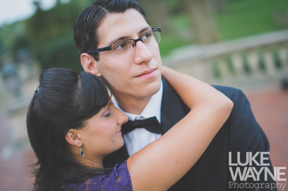 Woman hugging man in formal wear outdoors.