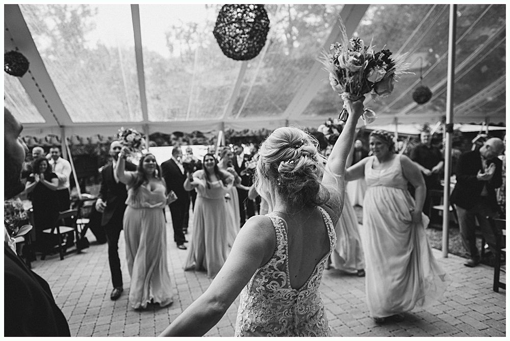 Barn interior with guests, food tables, and hanging glass globe lights.