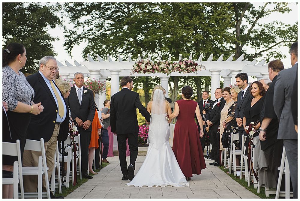 Wedding couple poses near trees, bride in a gown holds bouquet. One image shows them close, another shows them under a weeping willow.