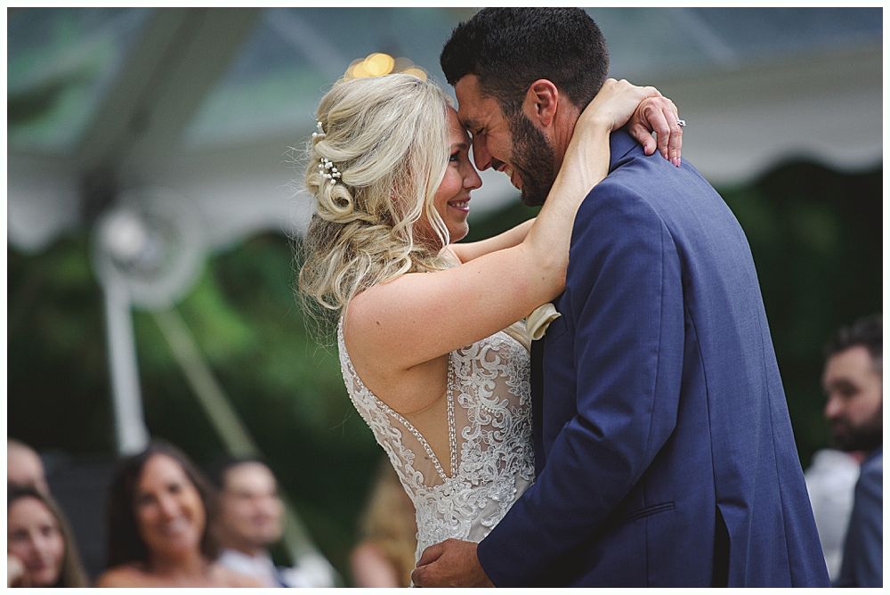 Woman in red gown throws bouquet at wedding reception. Man in suit reaches for it. Wooden interior.