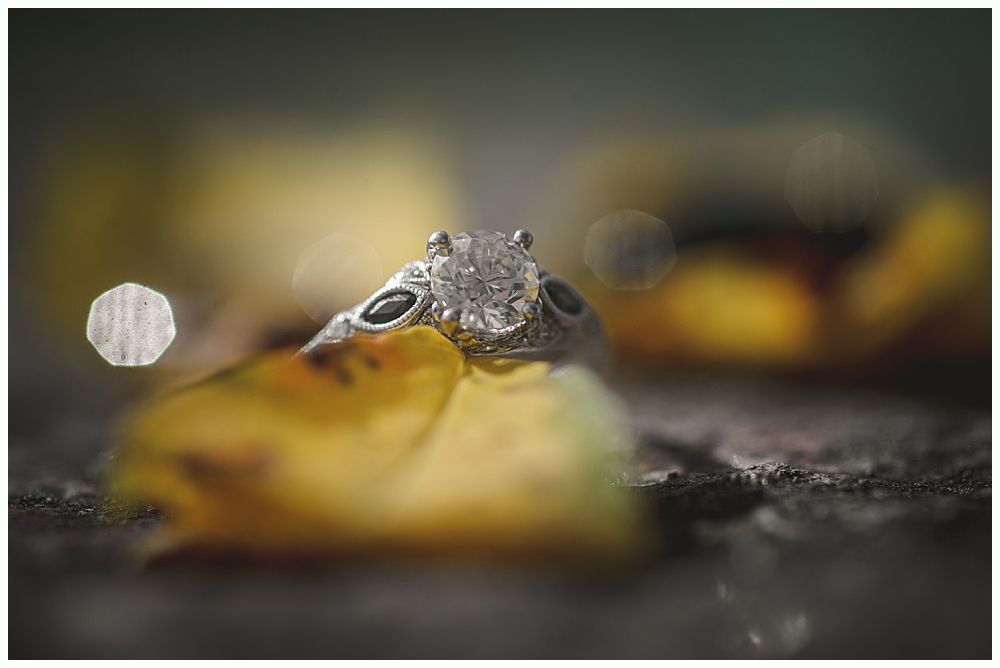 Woman putting on earrings, smiling. Dark background, wearing wedding dress.
