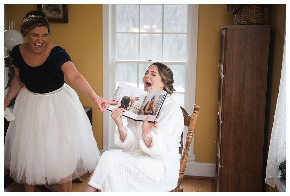 Woman putting on earrings, smiling. Dark background, wearing wedding dress.