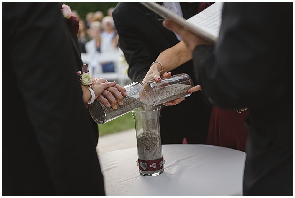 Woman in red gown throws bouquet at wedding reception. Man in suit reaches for it. Wooden interior.