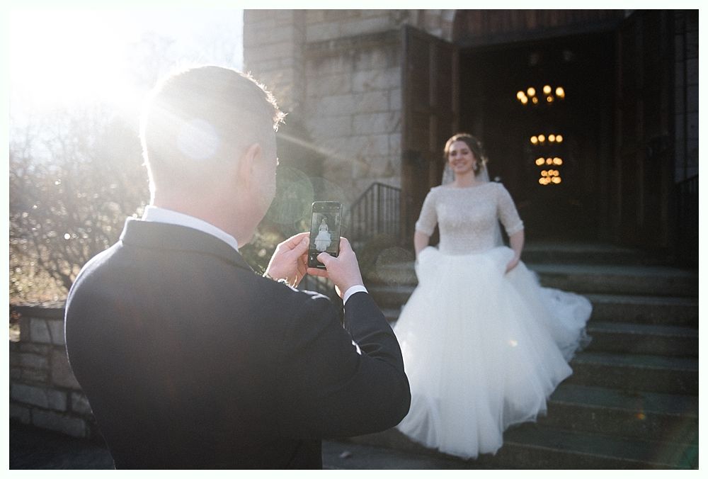 Couple dances at a wedding reception; chandelier and string lights in background.