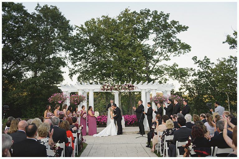 Wedding reception: couple dancing in a dark venue. Guests watch from tables.