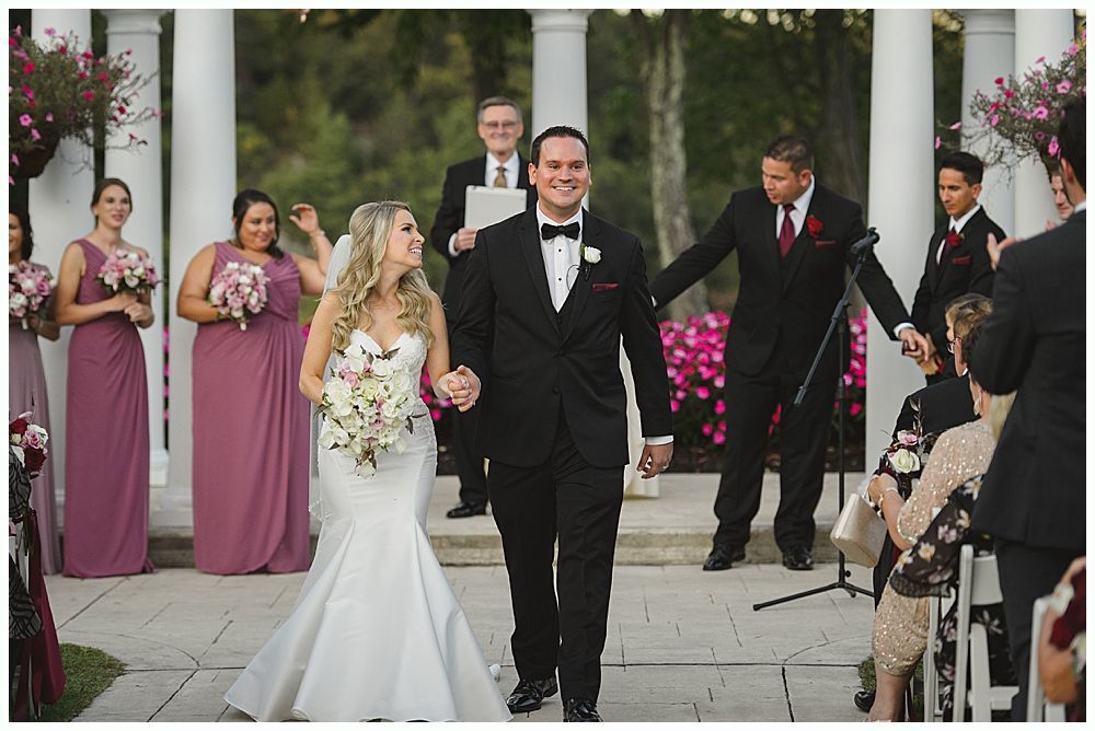 Couple dances at a wedding reception; chandelier and string lights in background.