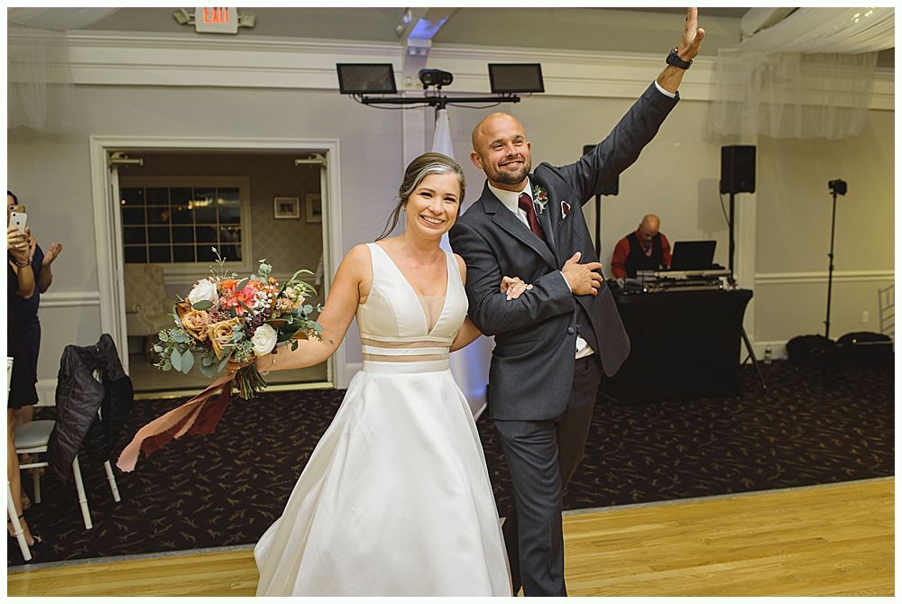 Wedding reception: couple dancing in a dark venue. Guests watch from tables.