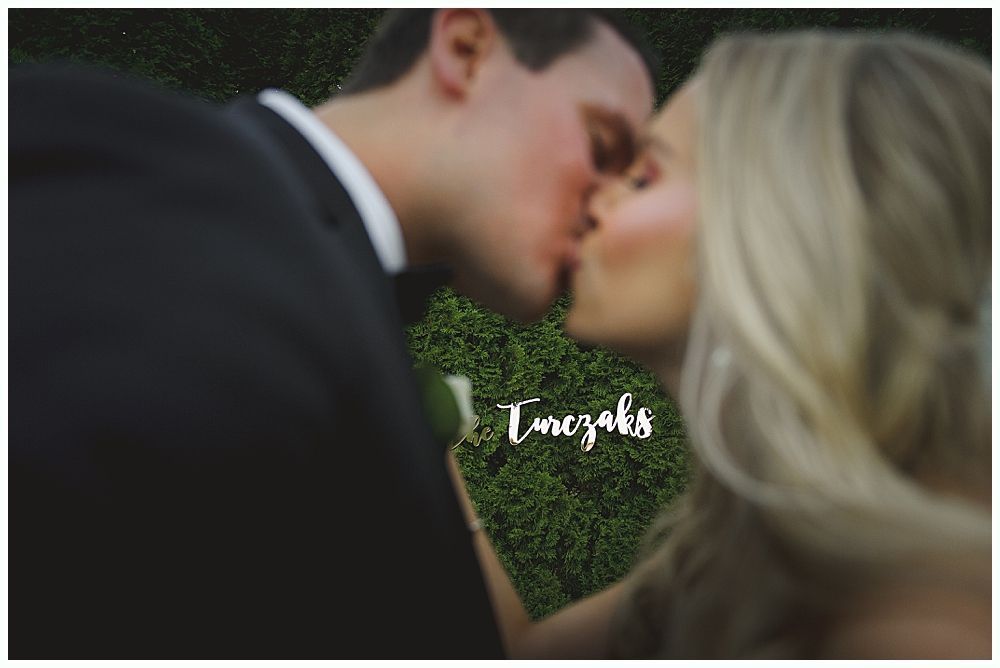 Newlyweds embrace on a dance floor, surrounded by guests at a wedding reception.
