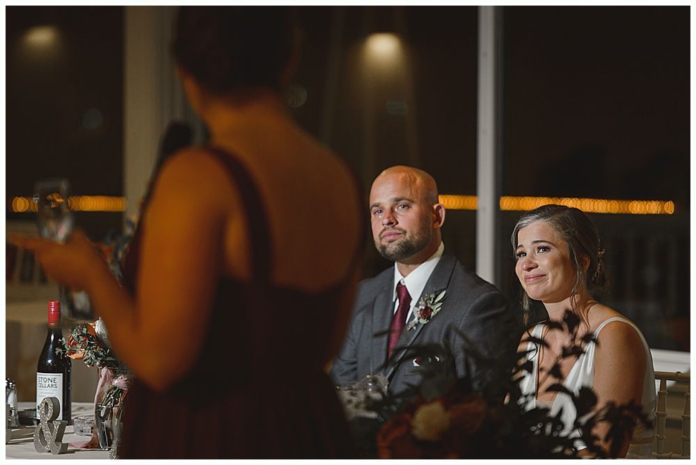 Newlyweds embrace on a dance floor, surrounded by guests at a wedding reception.