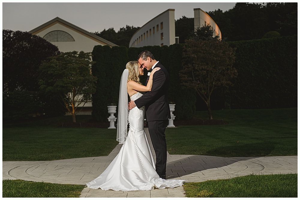 Woman in red dress giving a speech at a wedding. Bride smiles. Wooden interior.