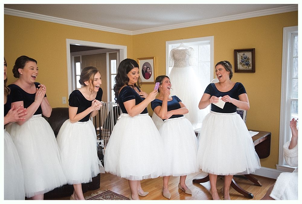 Bride in a white lace dress with veil, smiling, holding a bouquet of burgundy and green flowers.