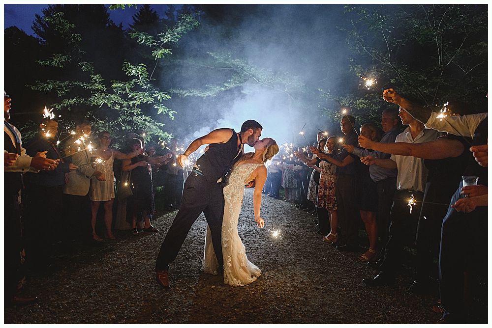 Wedding cake with figurines, on a wood slice. Rustic decor with blurred lights in the background.