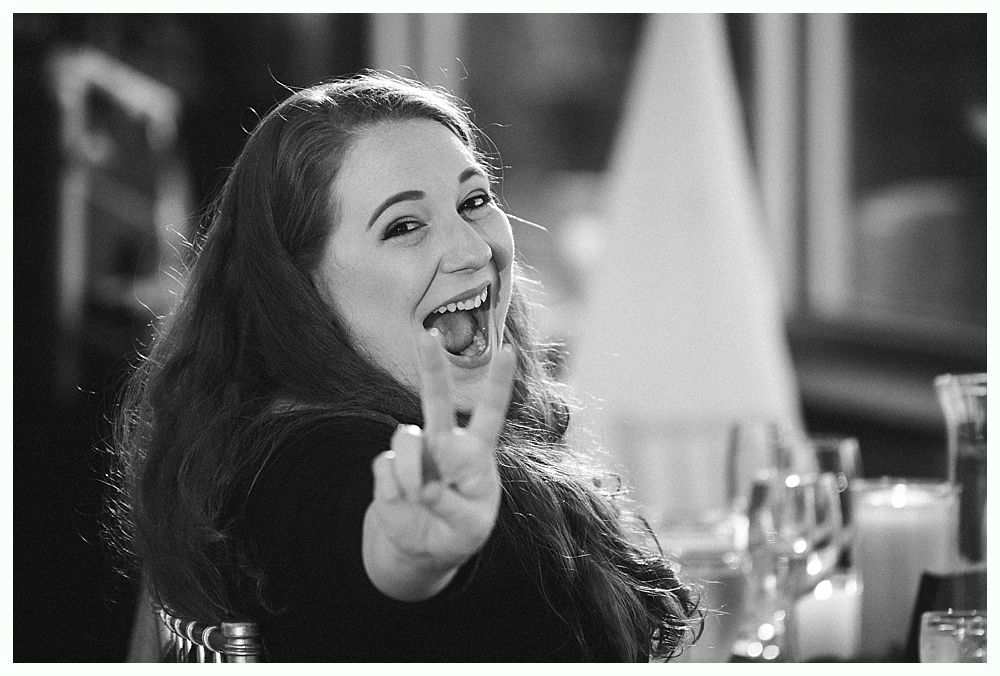 Wedding cake with figurines, on a wood slice. Rustic decor with blurred lights in the background.