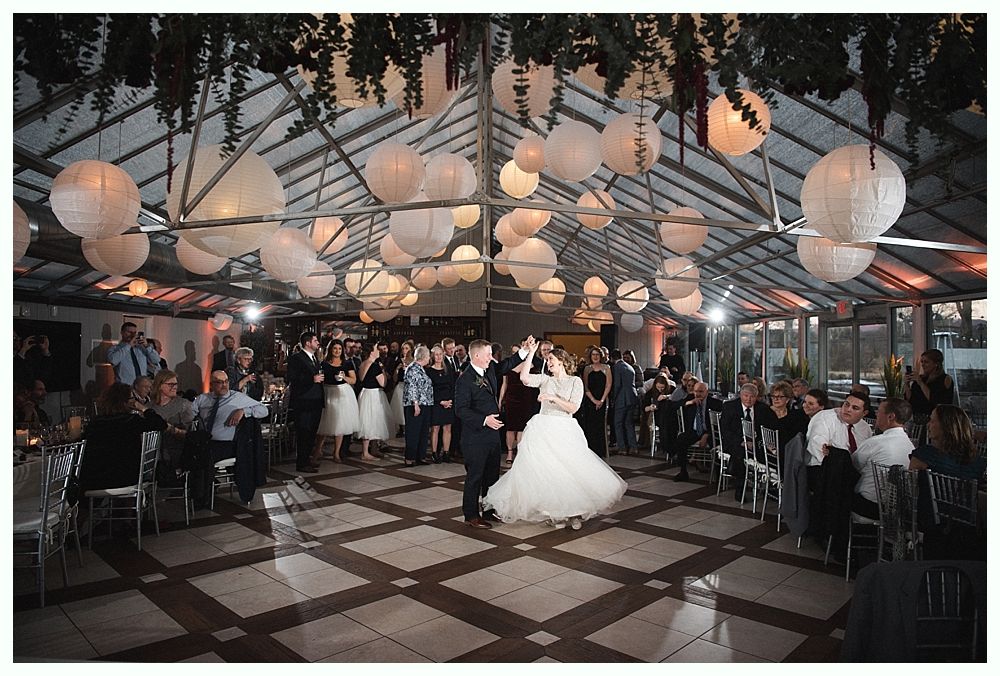 Wedding cake with figurines, on a wood slice. Rustic decor with blurred lights in the background.