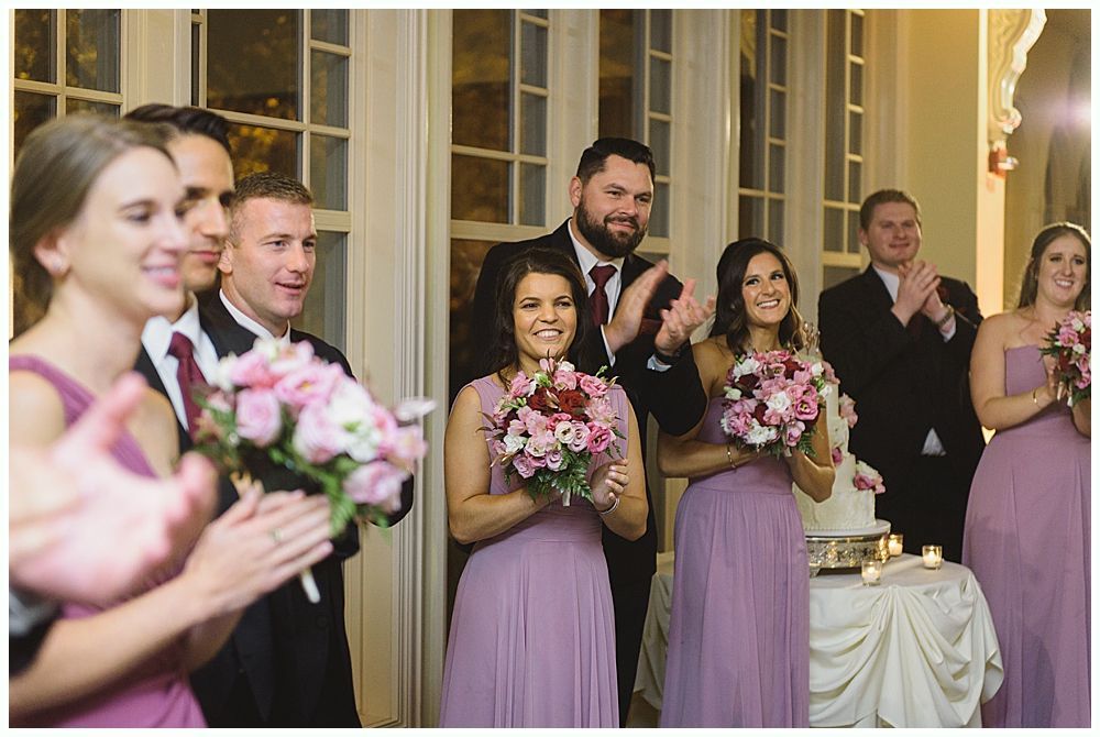 Man dancing with a drink, wearing a dress shirt and tie, inside a warmly lit venue.