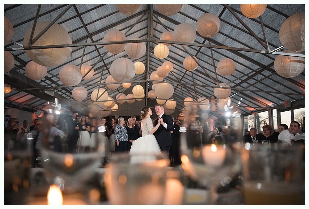 Wedding cake with figurines, on a wood slice. Rustic decor with blurred lights in the background.