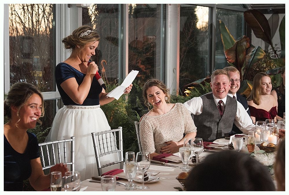Wedding cake with figurines, on a wood slice. Rustic decor with blurred lights in the background.