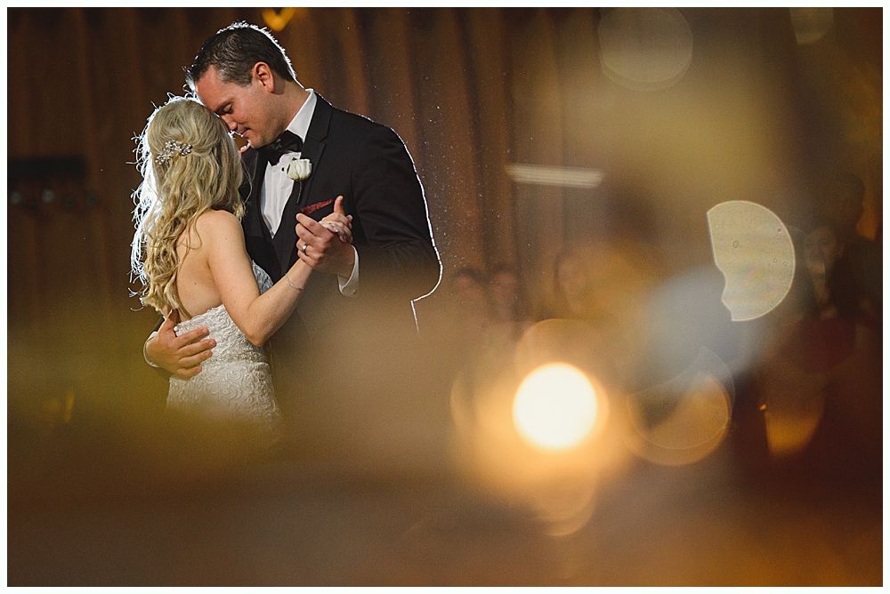 People at a wedding posing with a large cardboard cutout of a dog. Interior setting.