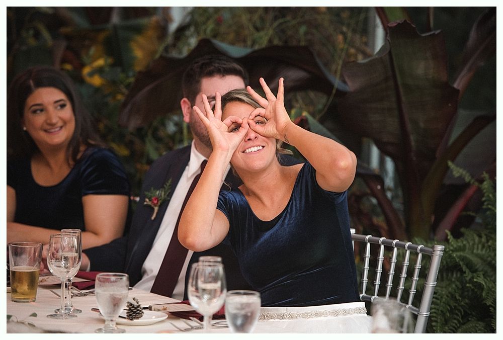 Wedding cake with figurines, on a wood slice. Rustic decor with blurred lights in the background.