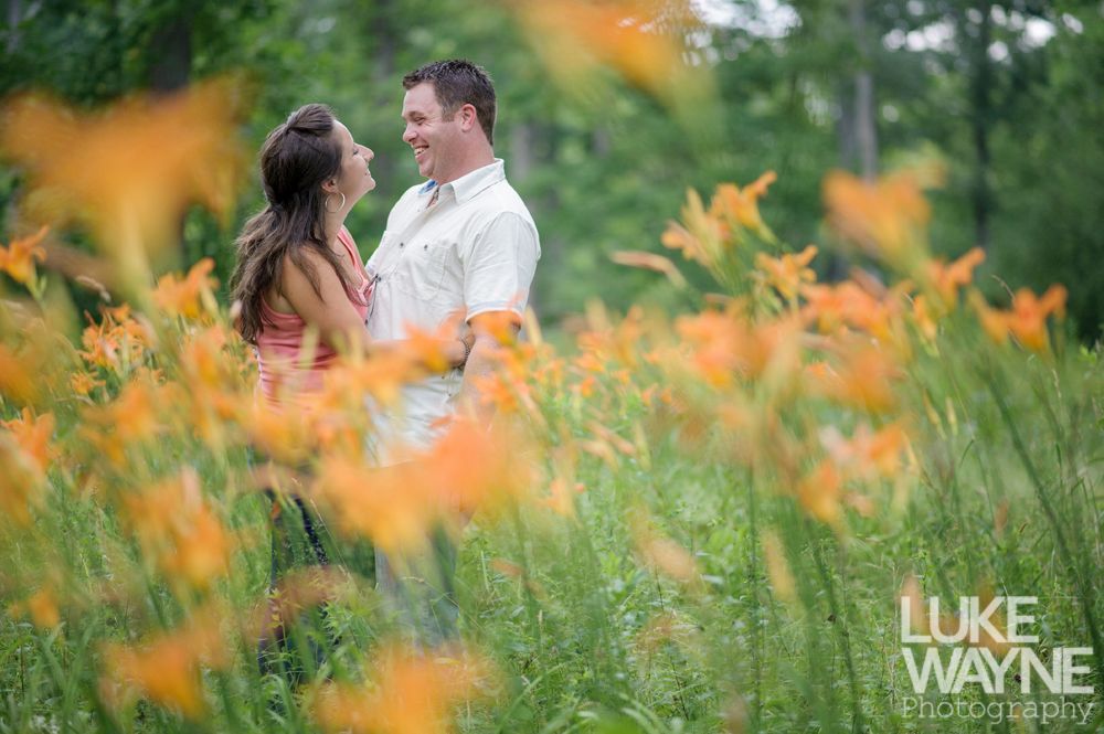 Couple smiling at each other in a field of orange flowers.