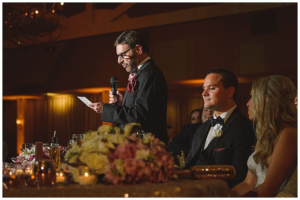 Group of people smiling, taking a selfie inside a rustic wooden barn at a wedding reception.