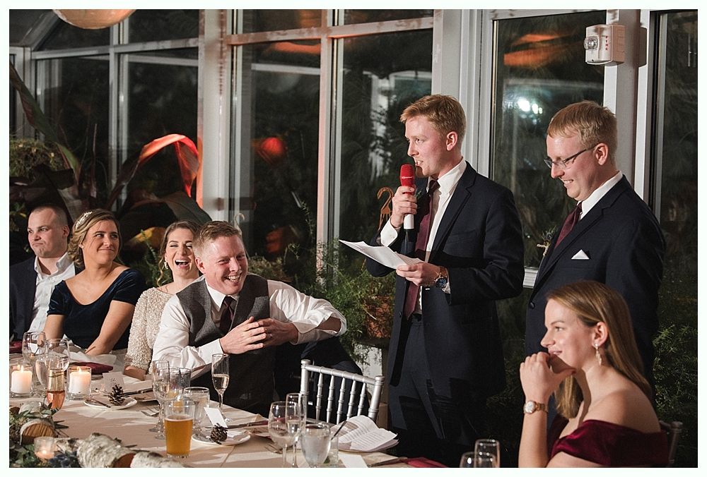 Wedding cake with figurines, on a wood slice. Rustic decor with blurred lights in the background.