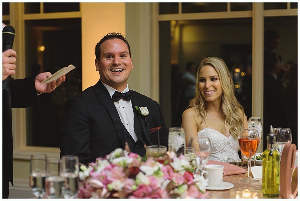Wedding reception: Bride and guests dance, arms crossed. Wooden interior, festive lights.