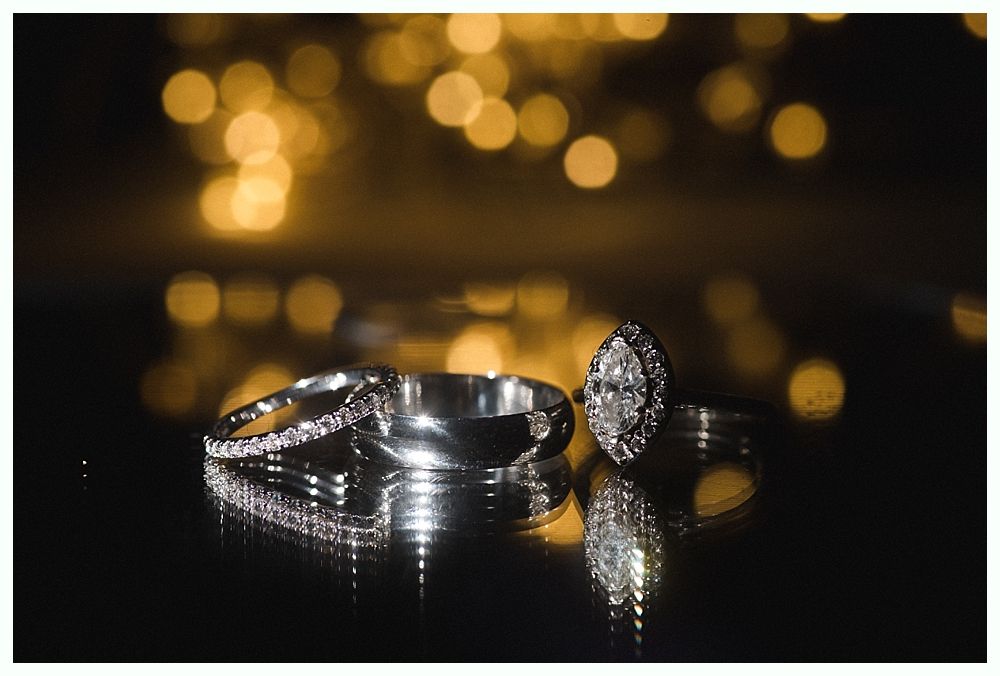 Wedding cake with figurines, on a wood slice. Rustic decor with blurred lights in the background.