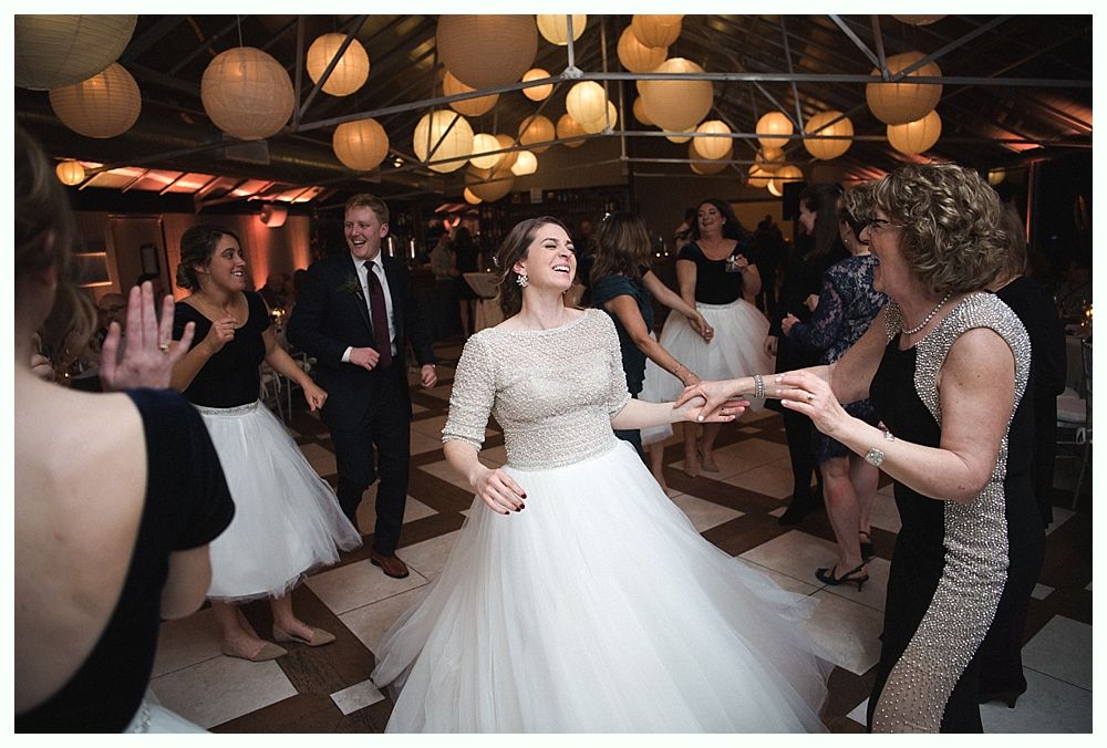Wedding cake with figurines, on a wood slice. Rustic decor with blurred lights in the background.