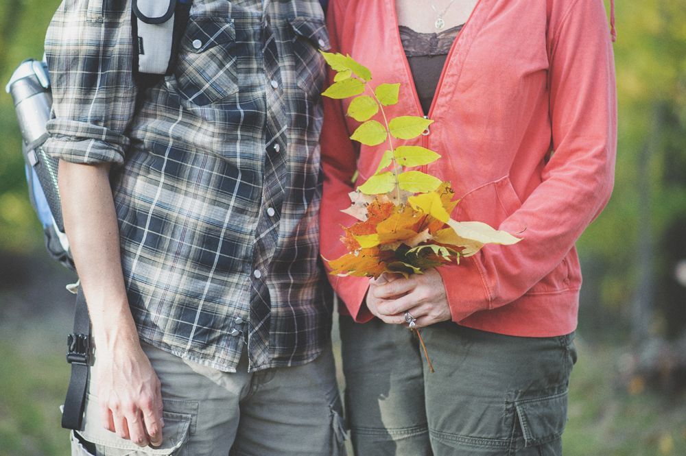 Bride facing camera, blurred. Two women, one smiling, one on phone, observe in a room.
