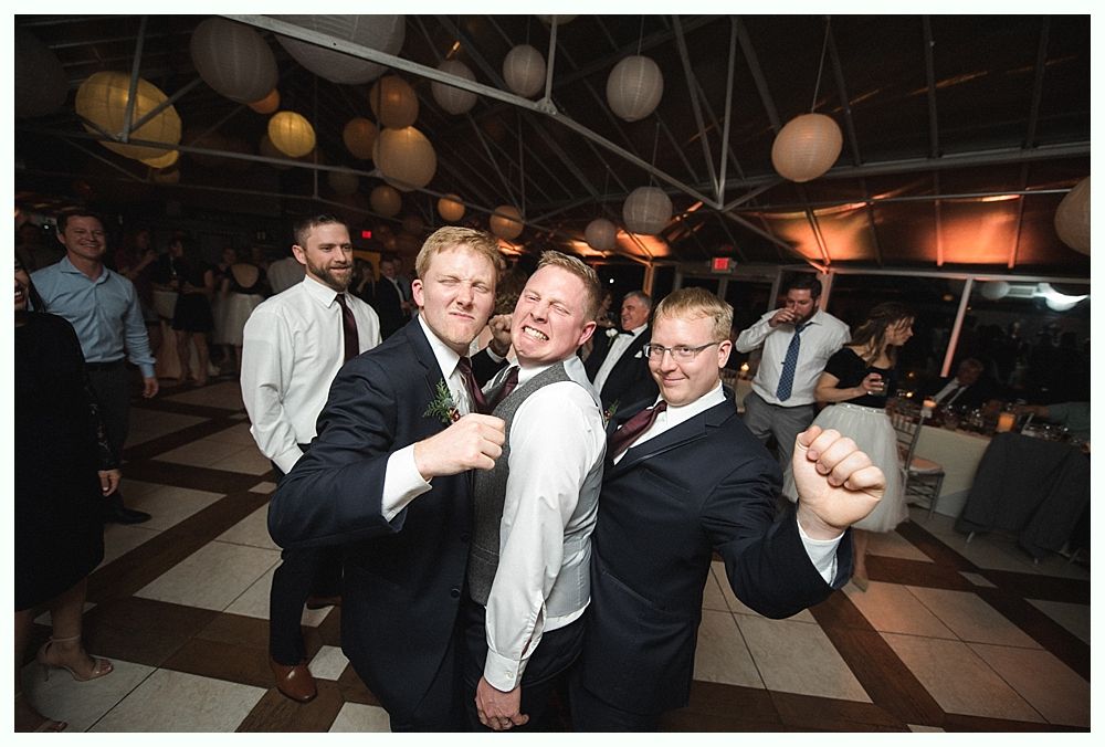 Wedding cake with figurines, on a wood slice. Rustic decor with blurred lights in the background.