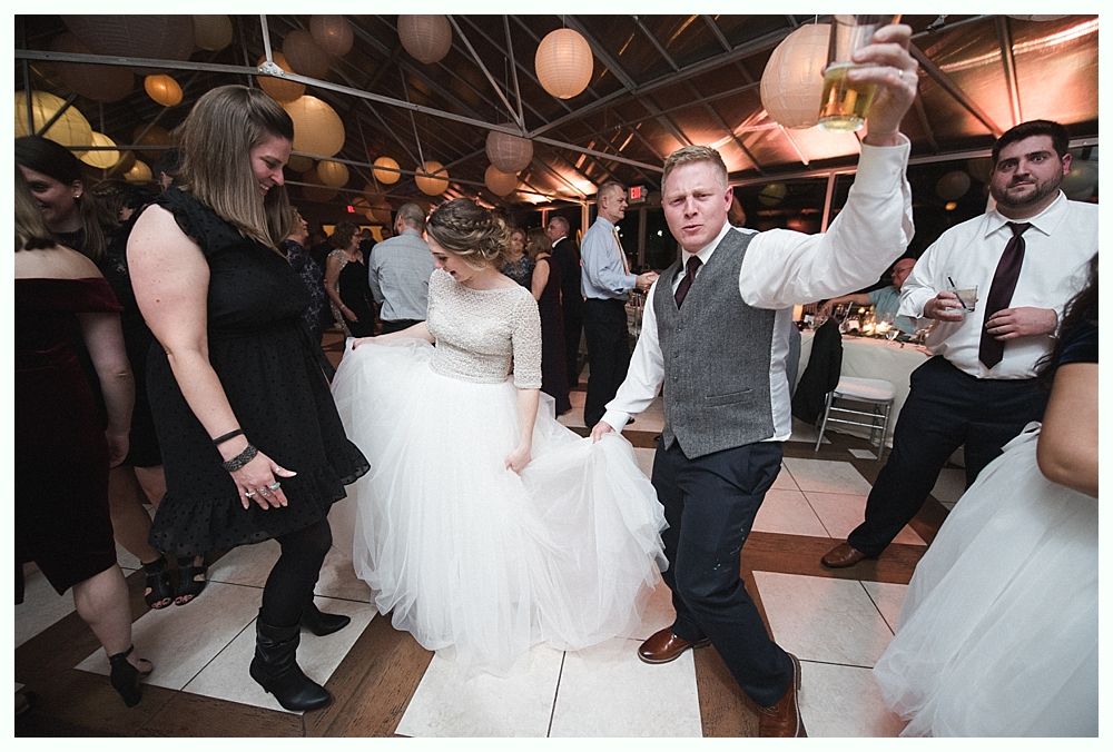 Wedding cake with figurines, on a wood slice. Rustic decor with blurred lights in the background.
