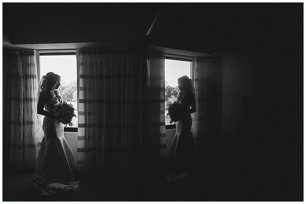 Bridesmaids in red dresses and shawls laugh with bride holding a bouquet outdoors.
