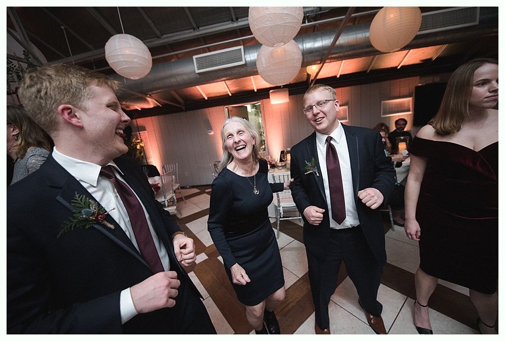 Wedding cake with figurines, on a wood slice. Rustic decor with blurred lights in the background.