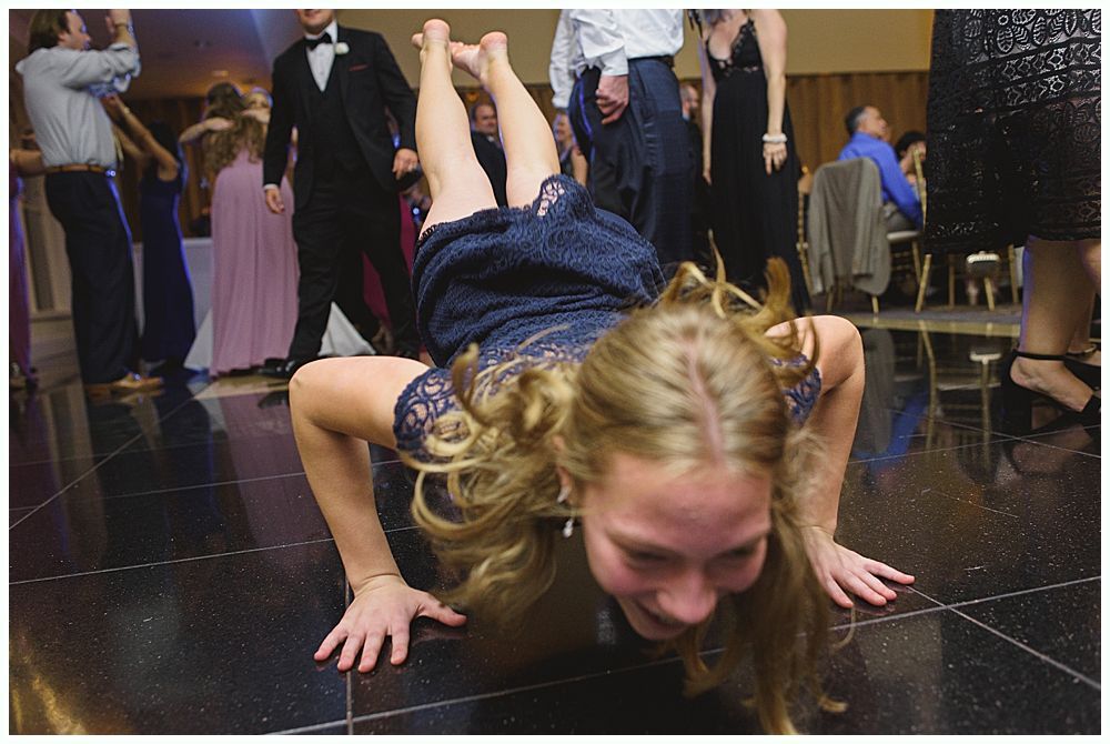 Bride and groom embrace outdoors, veil billowing, wedding bouquets visible.