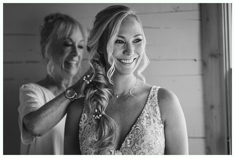 Bride in white dress with bridesmaids in red holding bouquets, smiling outdoors.