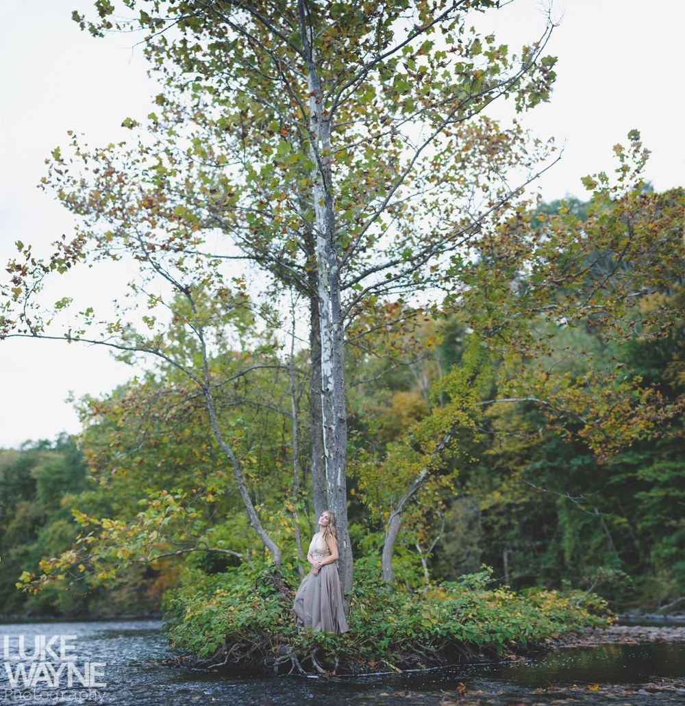 Couple sits on a rocky outcrop, distant building visible. He wears a blue jacket, she wears an orange skirt. Outdoors.