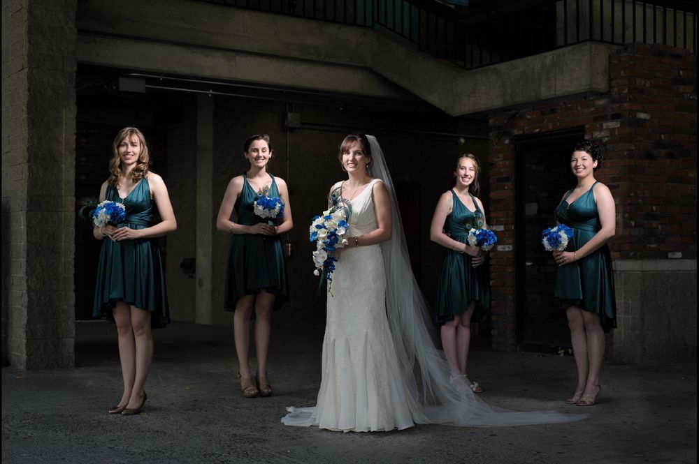 A bride is helped into her wedding dress. A bridesmaid fastens the corset back. The bride's shoes are visible.