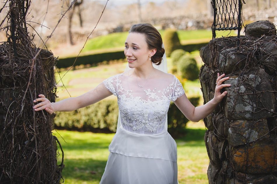 Bride with arms up, making a funny face, groom looking at his hand, cake cutting in background.
