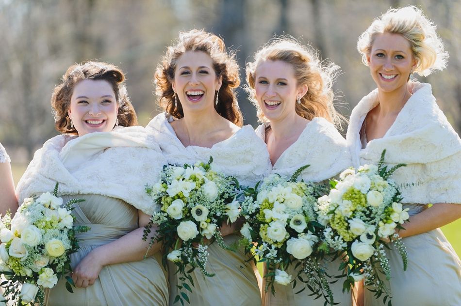 Bride with arms up, making a funny face, groom looking at his hand, cake cutting in background.