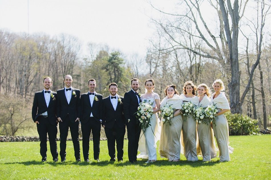 Bride with arms up, making a funny face, groom looking at his hand, cake cutting in background.