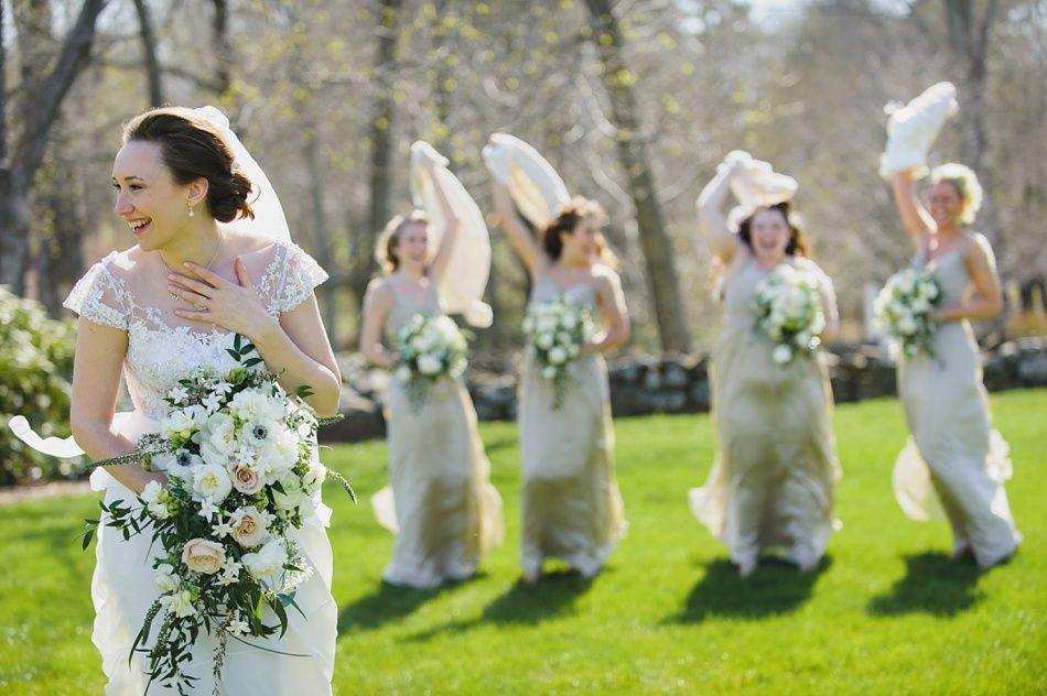 Bride with arms up, making a funny face, groom looking at his hand, cake cutting in background.