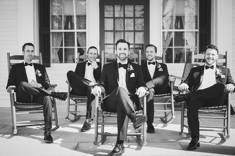 Bride with arms up, making a funny face, groom looking at his hand, cake cutting in background.