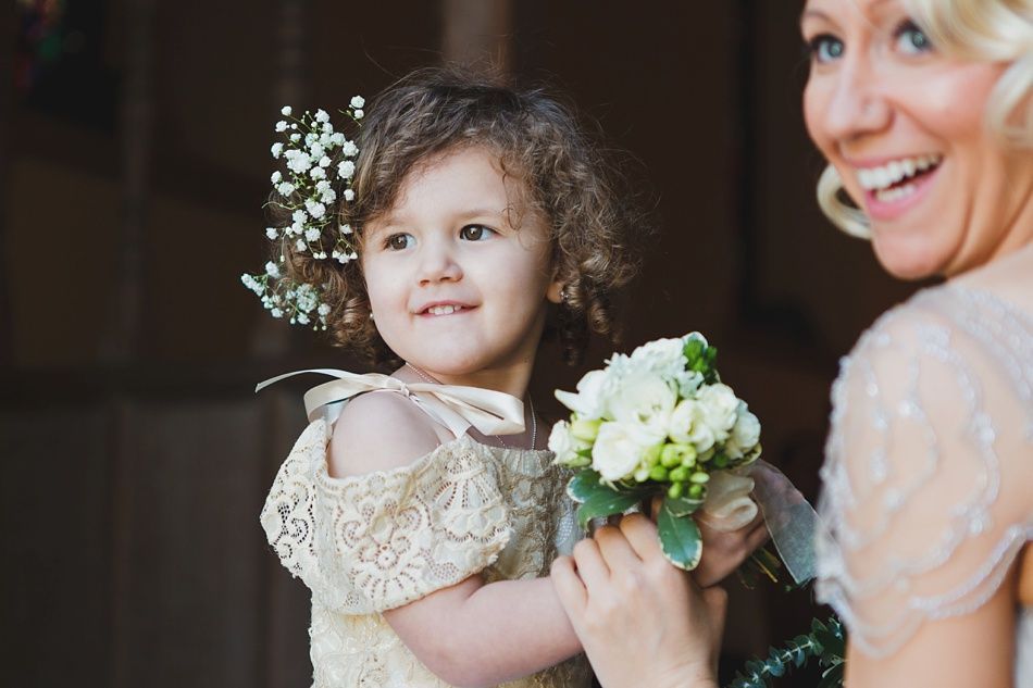 Bride with arms up, making a funny face, groom looking at his hand, cake cutting in background.