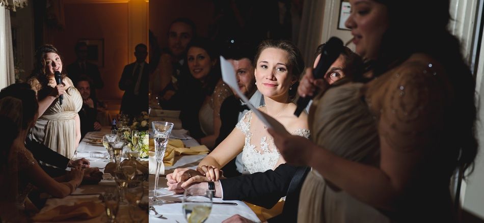 Bride with arms up, making a funny face, groom looking at his hand, cake cutting in background.