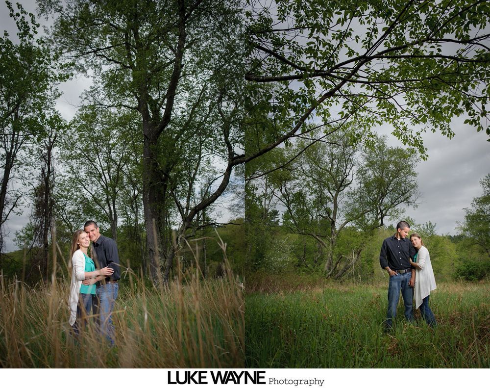Couple embraces in a field with trees in the background, both sides of the picture.