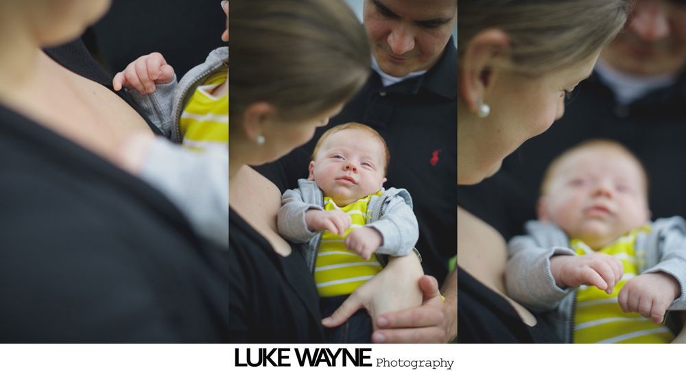 Parents gazing at baby in yellow and grey outfit.